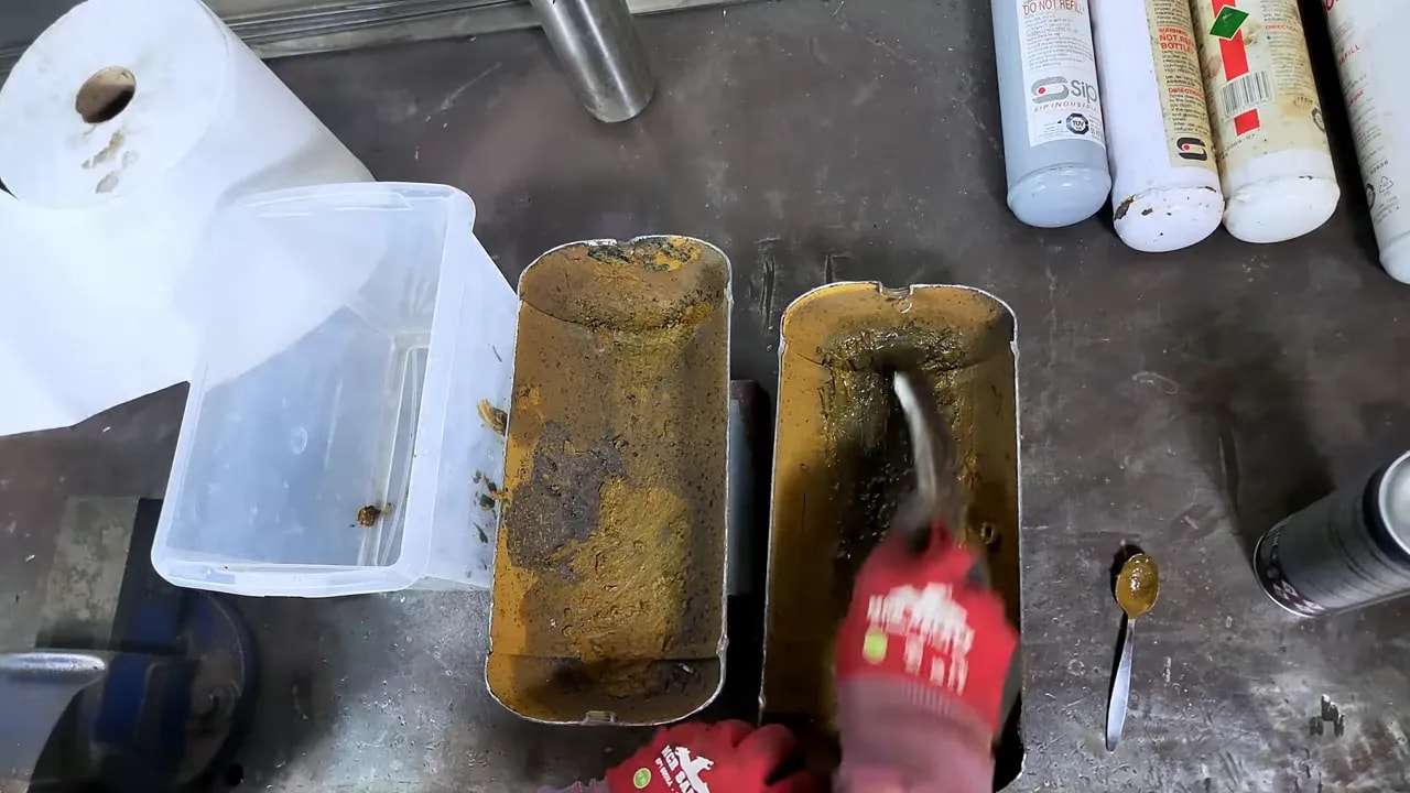Cut-open compressor tank halves with gritty corroded interior during cleaning