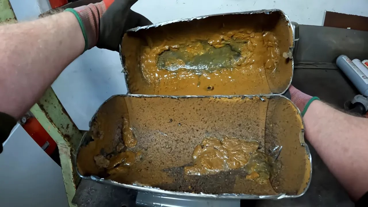 Cut open compressor tank interior with thick rusty goo and corrosion deposits