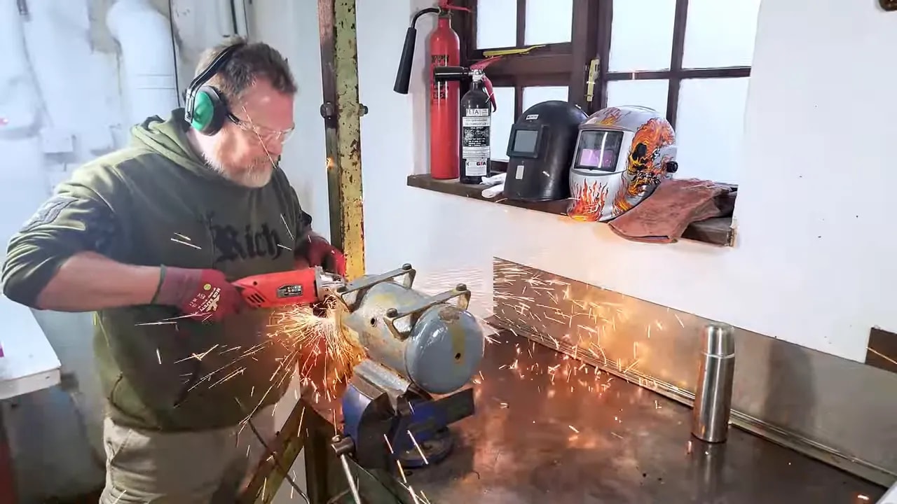 Workshop cutting of an old compressor tank with visible sparks and grinder