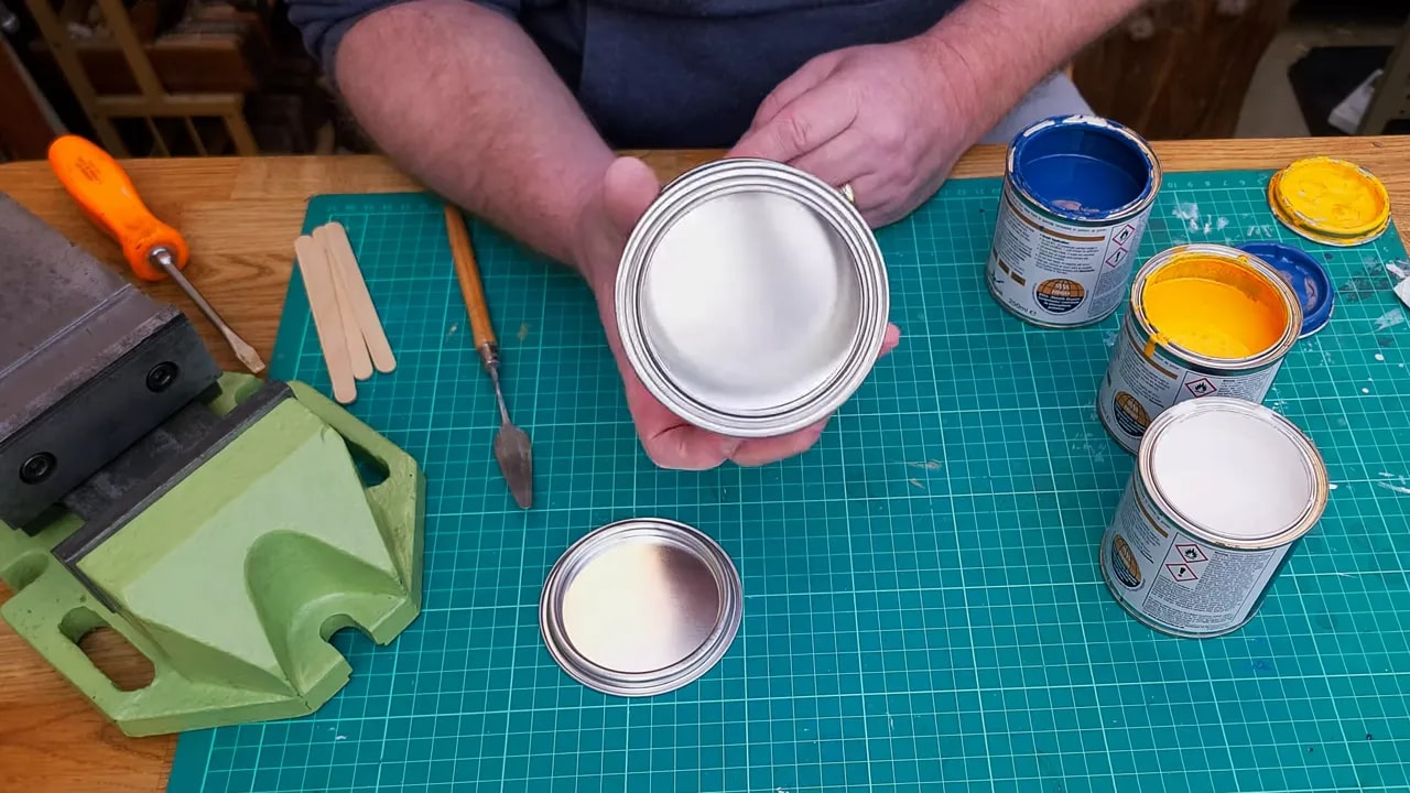 Mixing tin ready on a cutting mat with Hammerite cans showing white, blue, and yellow for custom colour mixing