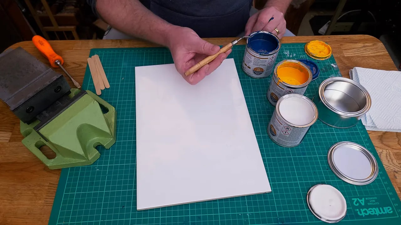 Blue and yellow Hammerite test mix dabbed onto a white tile on a workbench
