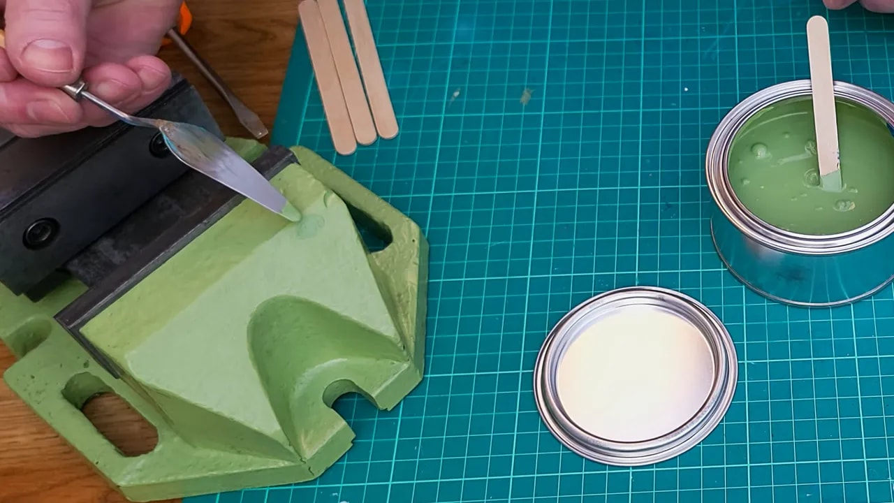 Stirred pale green test paint on a white tile ready for comparison