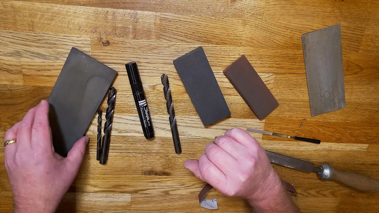 Workshop bench showing drill bits, slipstone, and diamond plates arranged on a wooden surface