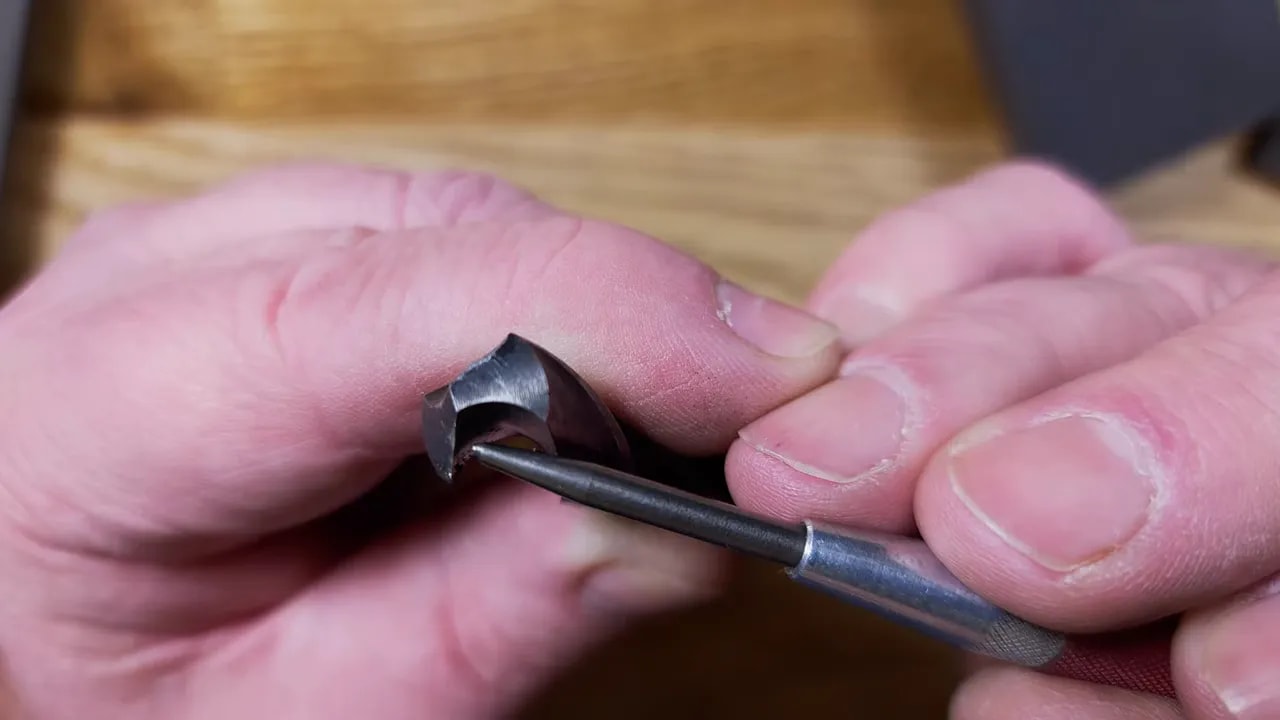 Close-up of twist drill bit cutting lip and flank being honed by hand with diamond plate