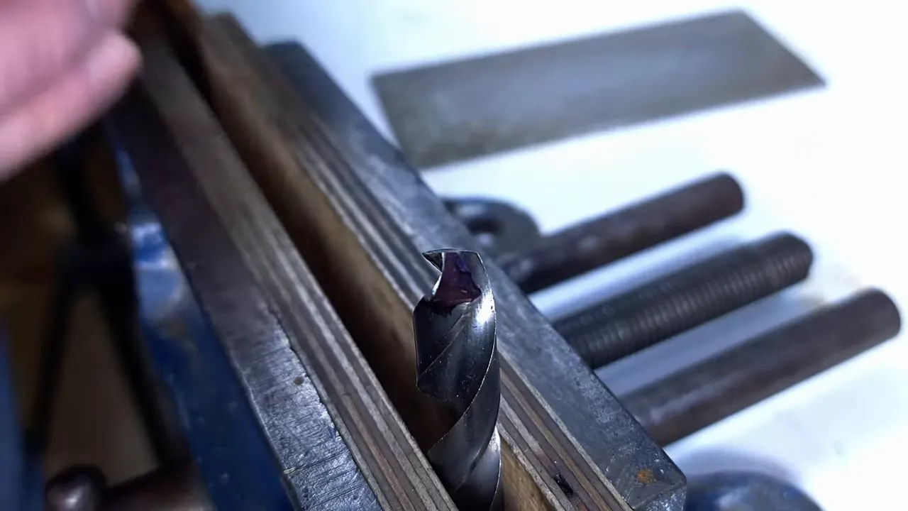 Close-up of a drill bit clamped in a vice with the cutting lip visible
