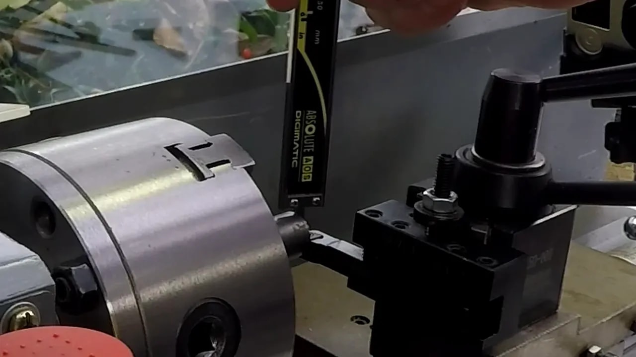 Depth measurement setup on a lathe using a caliper depth probe near the bar
