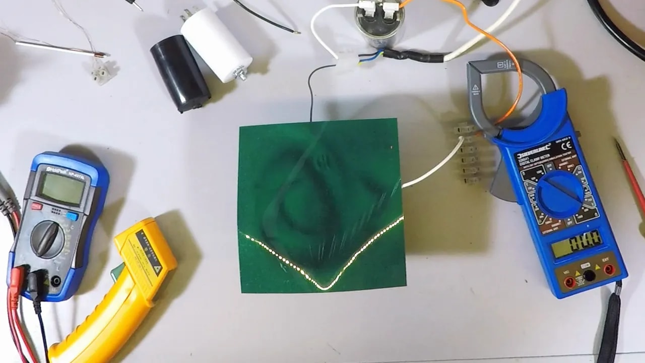 Green magnetic viewing film on the bench showing dark field pattern beside a blue meter and stator