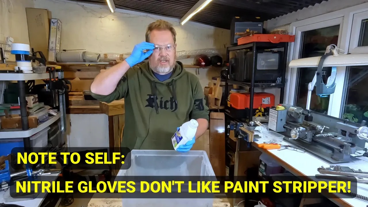 Person wearing blue gloves with on-screen text warning that nitrile gloves do not like paint stripper