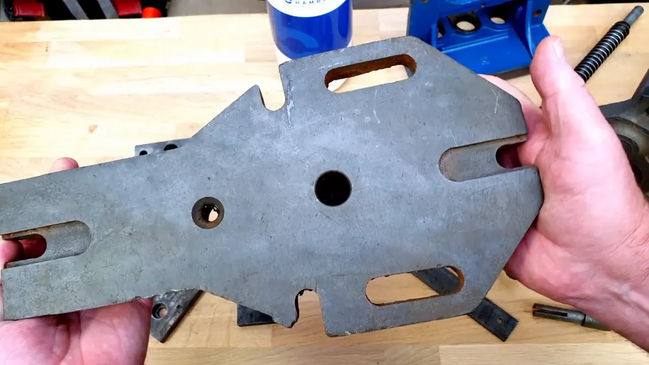 Large cleaned grey steel vice plate held above a workbench