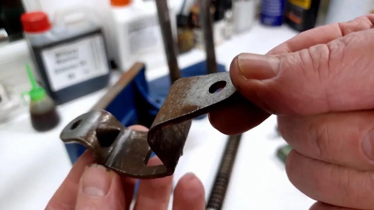 Cleaned metal quick-release component held above dismantled blue woodworking vice parts