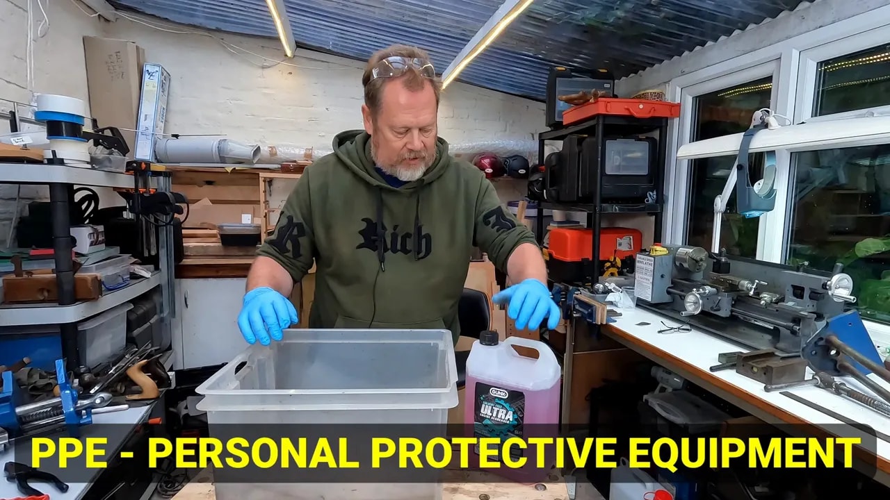 Gloved hands beside a plastic cleaning tub and Gunk Ultra container with PPE text on screen