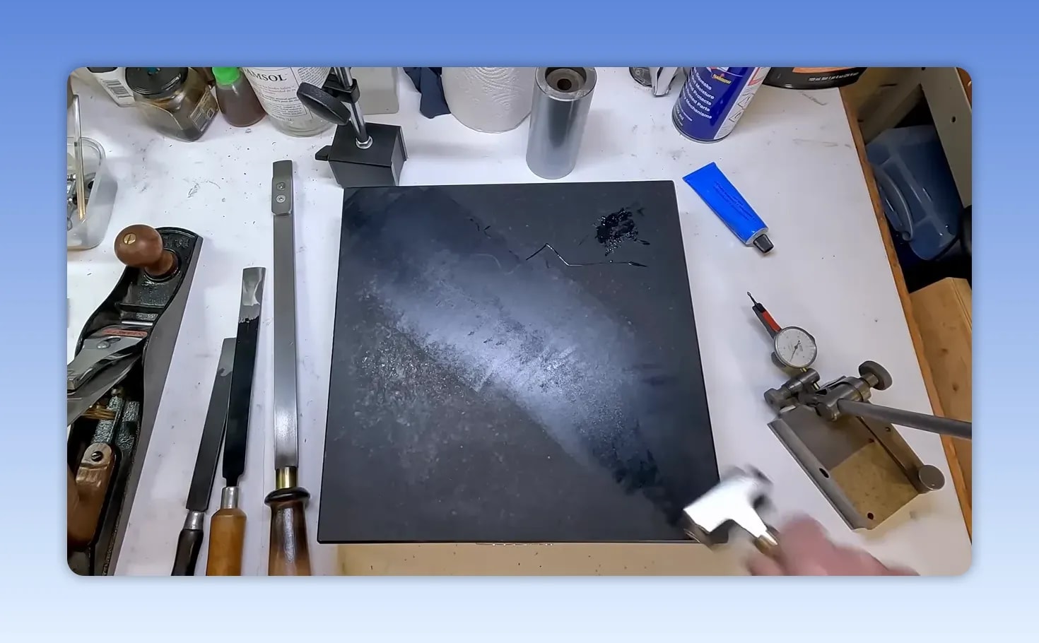 Engineers blue being rolled across a black granite surface plate