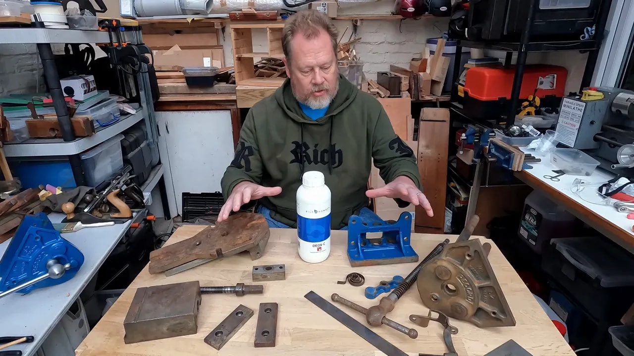 Heavily rusted steel vice plate and smaller rusty machine parts on a wooden bench